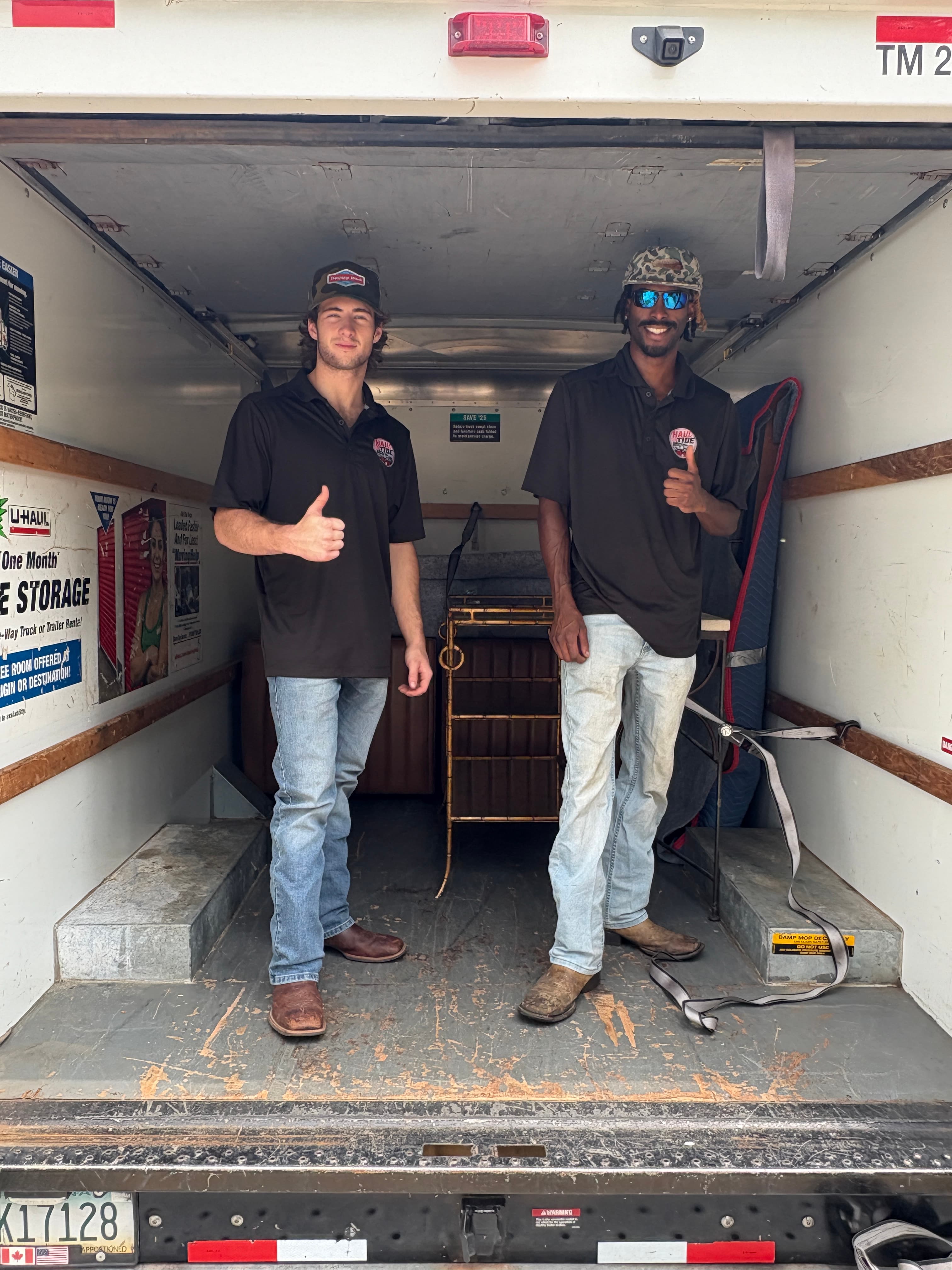 Haul Tide mover giving a thumbs up beside a loaded covered trailer