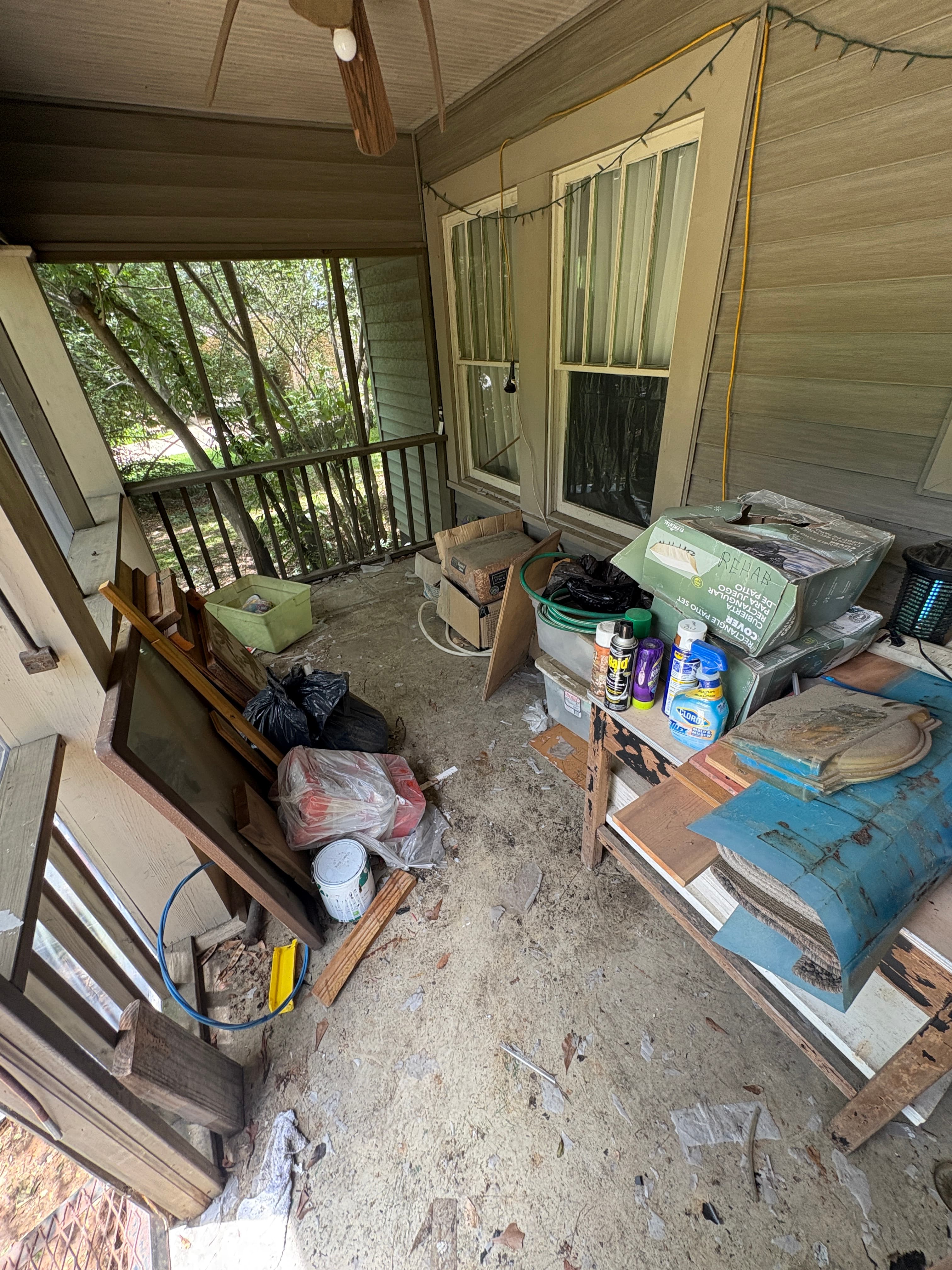 Porch piled with discarded furniture and debris before cleanup