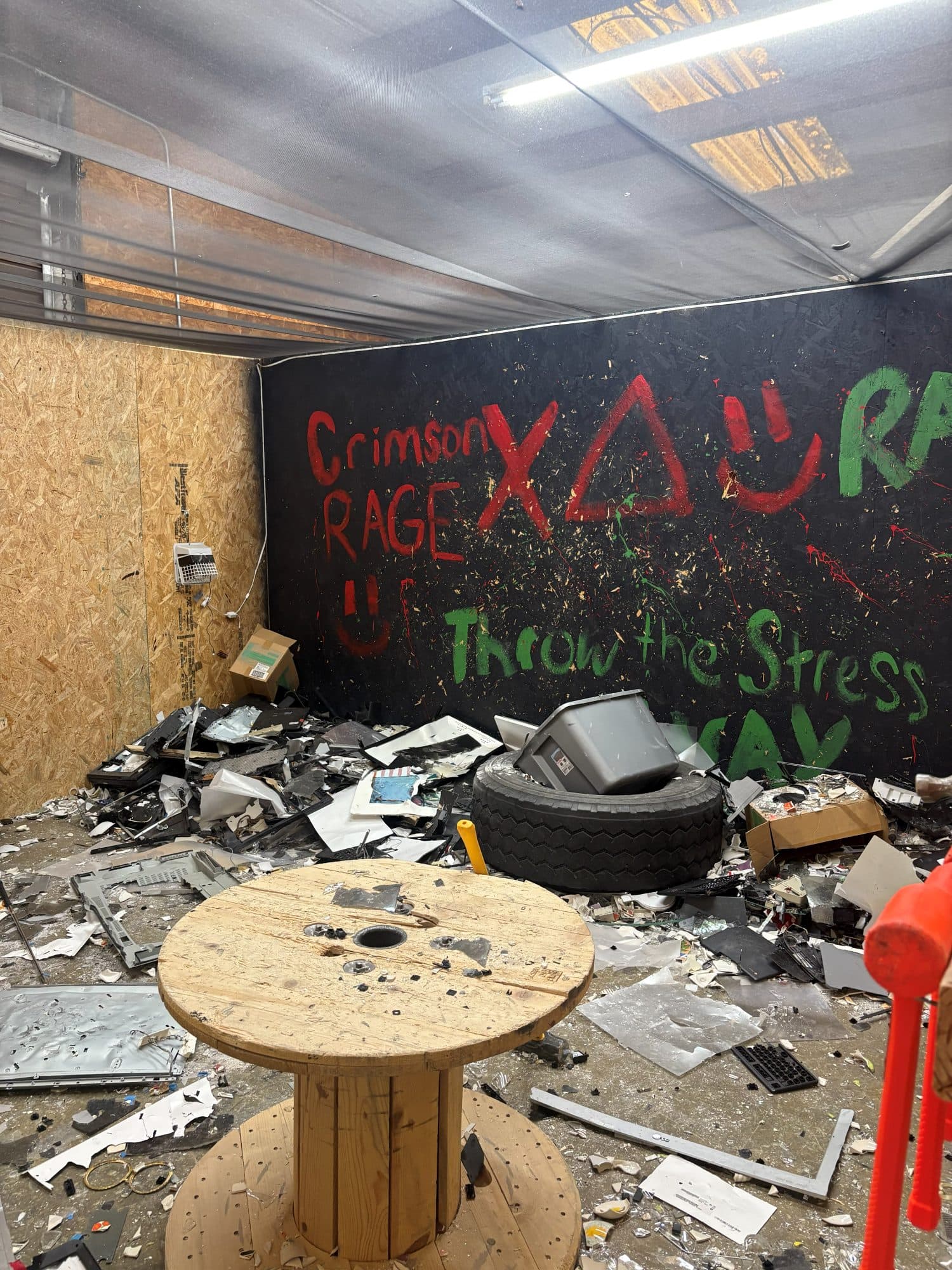 Debris and smashed appliances piled in a rage room before removal